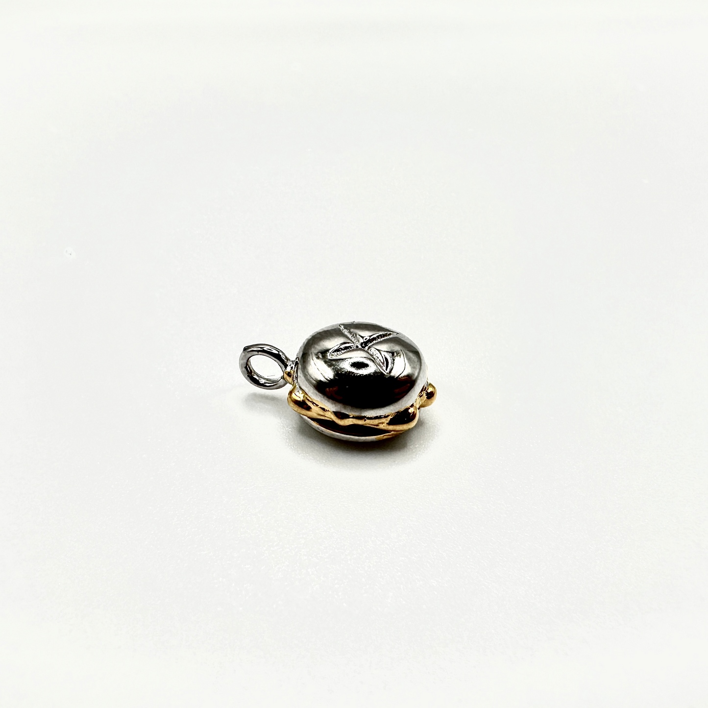 Edler Anhänger in Form des traditionellen „3 im Weggla“ – einem Nürnberger Bratwurstbrötchen. Die detailreiche Miniatur ist aus einer Kombination von Silber und Vergoldung gefertigt, wobei das glänzende Silber die Oberfläche des Brötchens darstellt und die goldfarbenen Akzente die Wurst und die unteren Partien hervorheben. Der Anhänger liegt auf einem schlichten weißen Hintergrund und verfügt über eine kleine Öse zur Befestigung an einer Kette oder einem Armband.