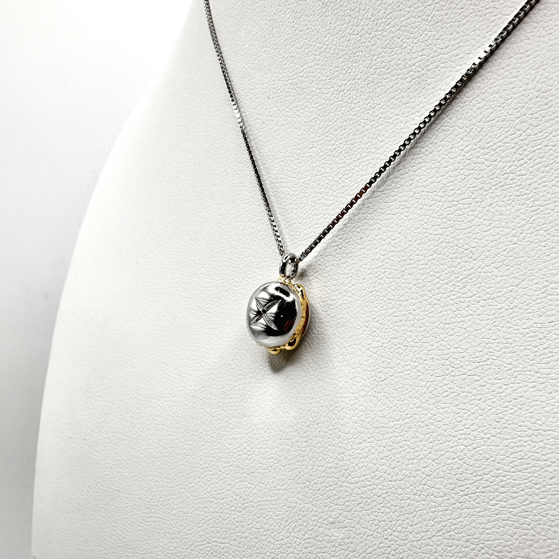 Eine elegante Kette mit einem einzigartigen Anhänger in Form des traditionellen fränkischen „3 im Weggla“. Der Anhänger kombiniert Silber- und Goldtöne, wobei das glänzende Silberbrötchen mit filigranen Details verziert ist. Die feine Silberkette unterstreicht die edle Optik des Schmuckstücks, das an einem weißen Schmuckdisplay präsentiert wird. Ein stilvolles Accessoire für Bratwurst-Liebhaber mit Heimatverbundenheit.