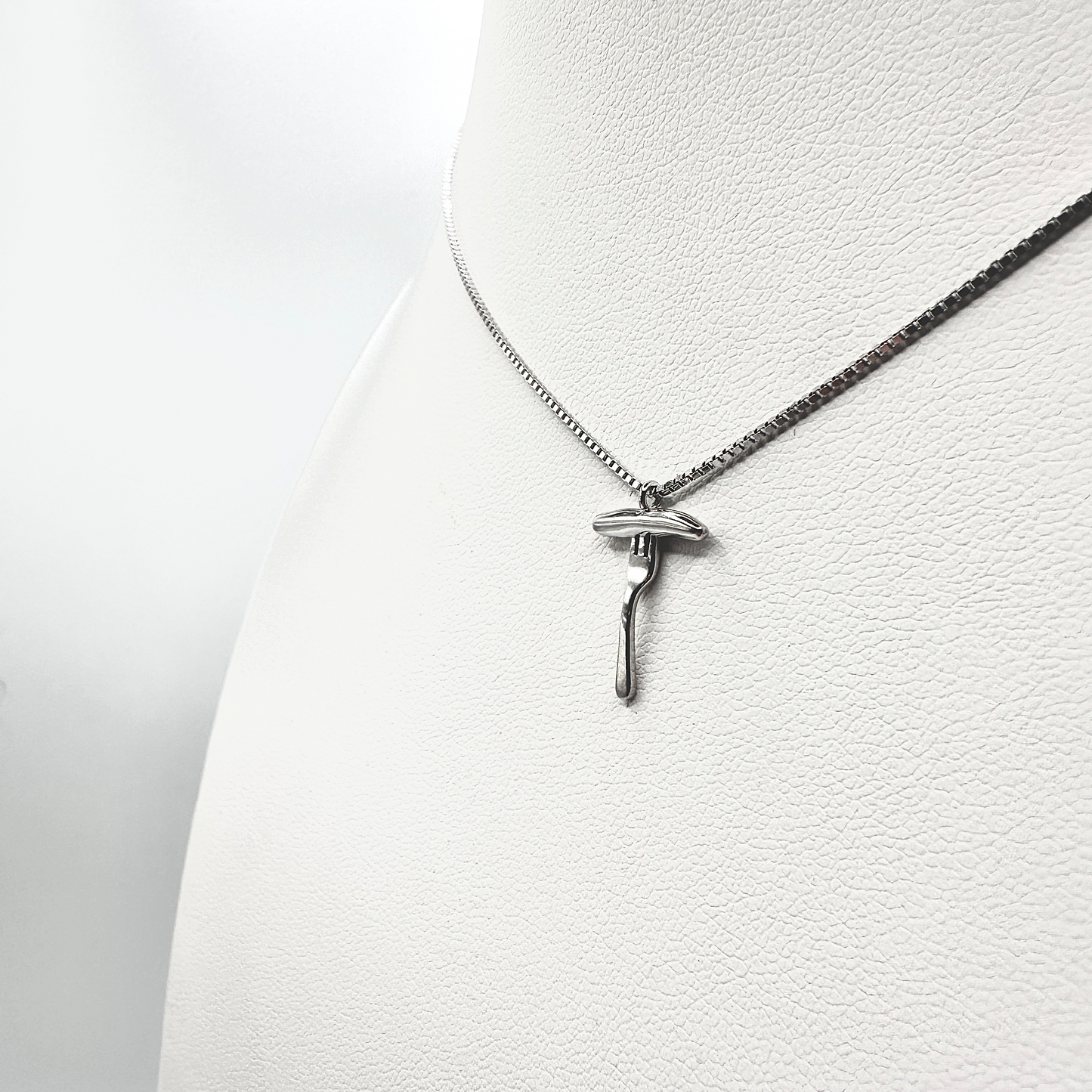 Eine silberne Halskette mit einem filigranen Anhänger in Form einer Bratwurst auf einer Gabel wird an einem weißen Schmuckdisplay präsentiert. Der detailreiche Anhänger zeigt eine realistisch gestaltete Bratwurst, die auf einer Gabel ruht, und hebt die glänzende, hochwertige Verarbeitung hervor. Die dezente Kette ergänzt das stilvolle Design, das Tradition und Eleganz verbindet.