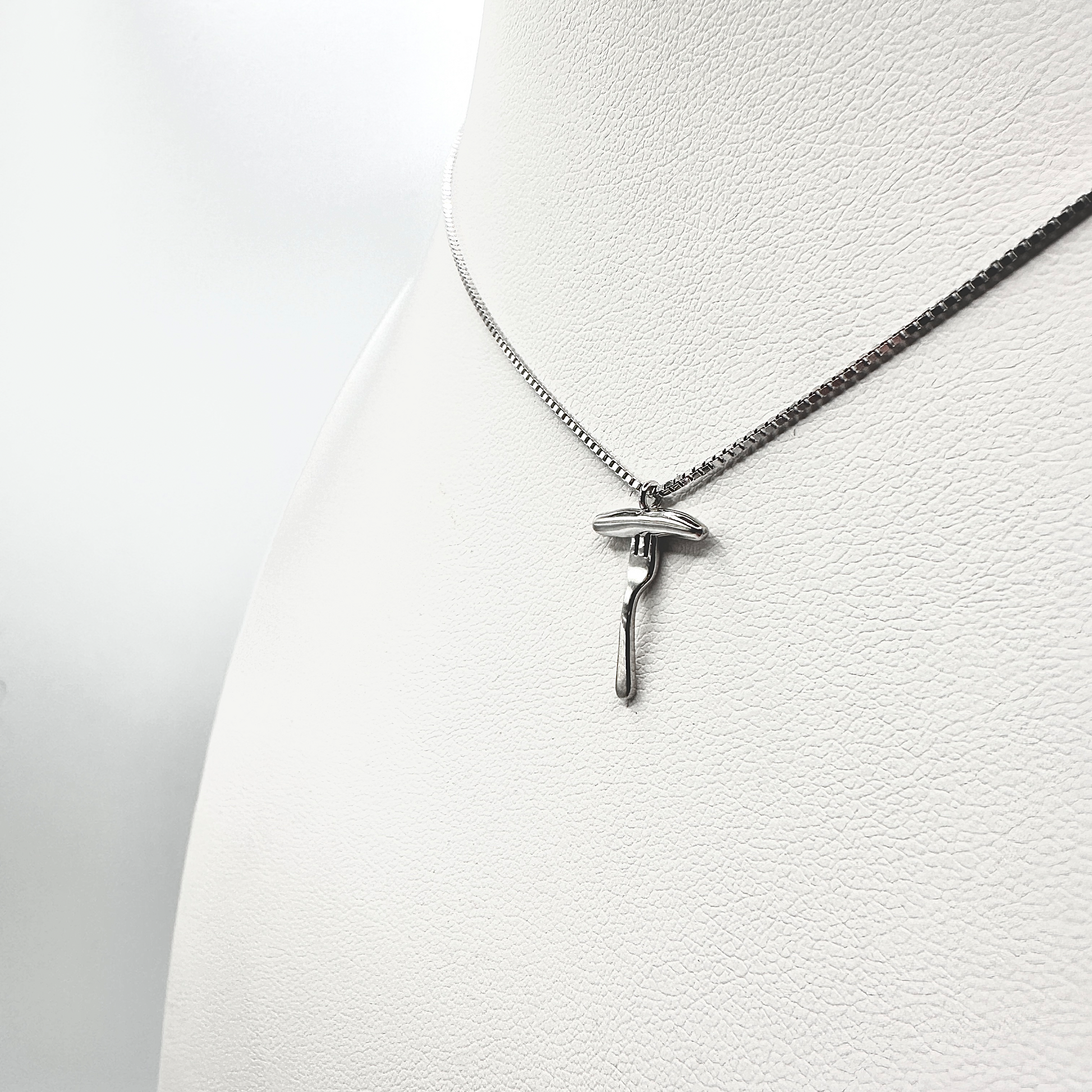 Eine silberne Halskette mit einem filigranen Anhänger in Form einer Bratwurst auf einer Gabel wird an einem weißen Schmuckdisplay präsentiert. Der detailreiche Anhänger zeigt eine realistisch gestaltete Bratwurst, die auf einer Gabel ruht, und hebt die glänzende, hochwertige Verarbeitung hervor. Die dezente Kette ergänzt das stilvolle Design, das Tradition und Eleganz verbindet.