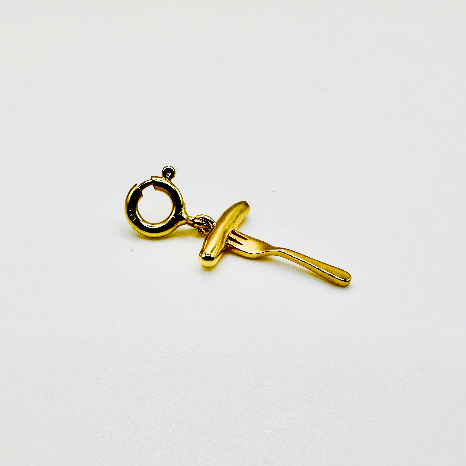 Vergoldeter Anhänger in Form einer Bratwurst auf einer Gabel, gefertigt aus Sterling Silber (925) mit 3 Micron Vergoldung. Der hochwertige Charm ist mit einem praktischen Federring-Verschluss versehen, wodurch er sich mühelos an Ketten oder Armbändern befestigen lässt. Ein edles und originelles Schmuckstück für Liebhaber der fränkischen Bratwurst und traditioneller Handwerkskunst.