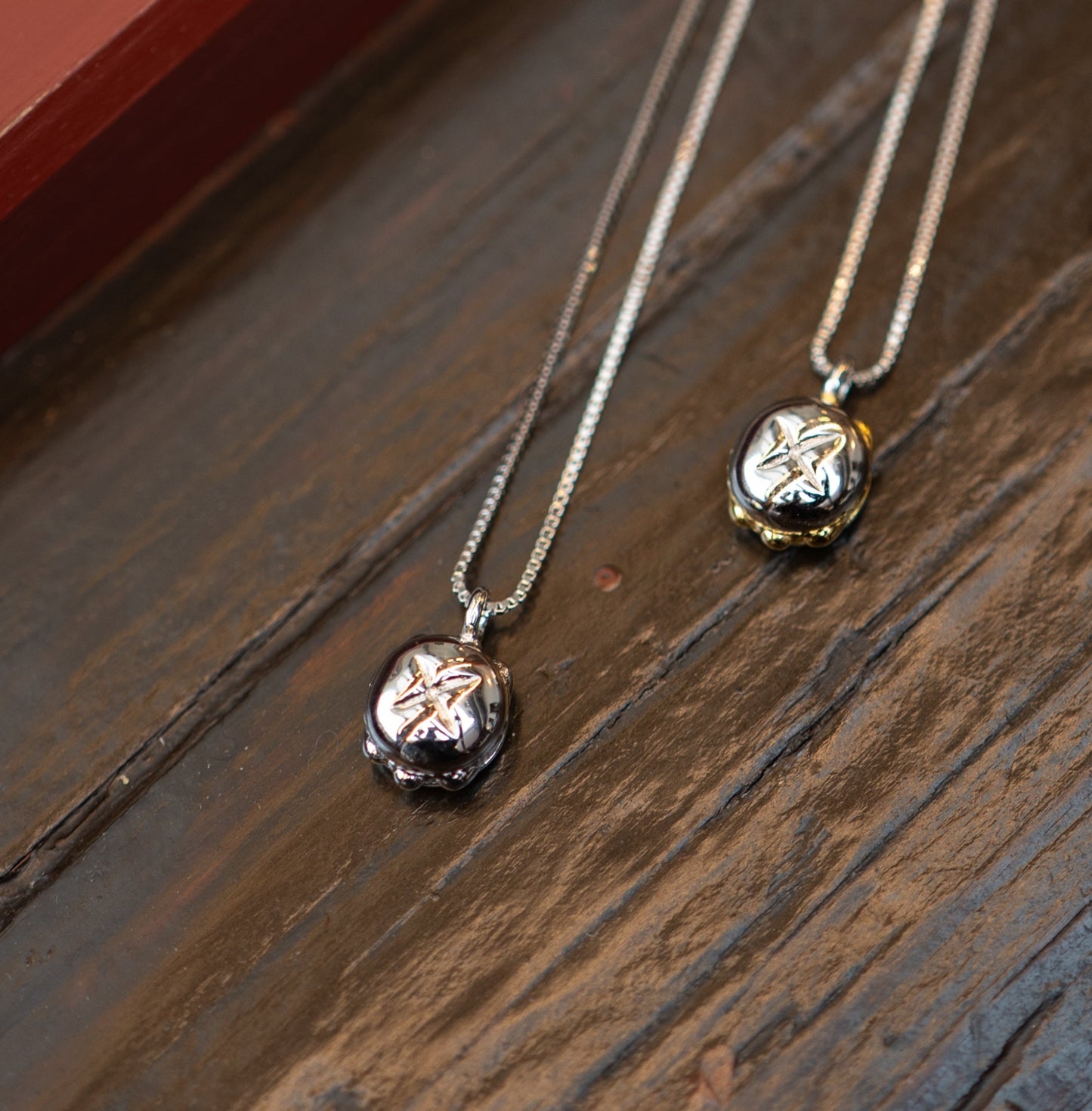 Silberne Halskette mit einem Anhänger in Form von „3 im Weggla“, kunstvoll gestaltet mit feinen Details, liegend auf einer rustikalen Holzoberfläche.