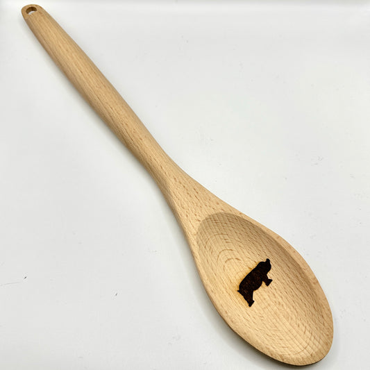 Ein hochwertiger Kochlöffel aus Holz mit einer Gravur eines Schweinsymbols in der Laffe. Der Löffel besticht durch seine natürliche Maserung und das schlichte, aber stilvolle Design.