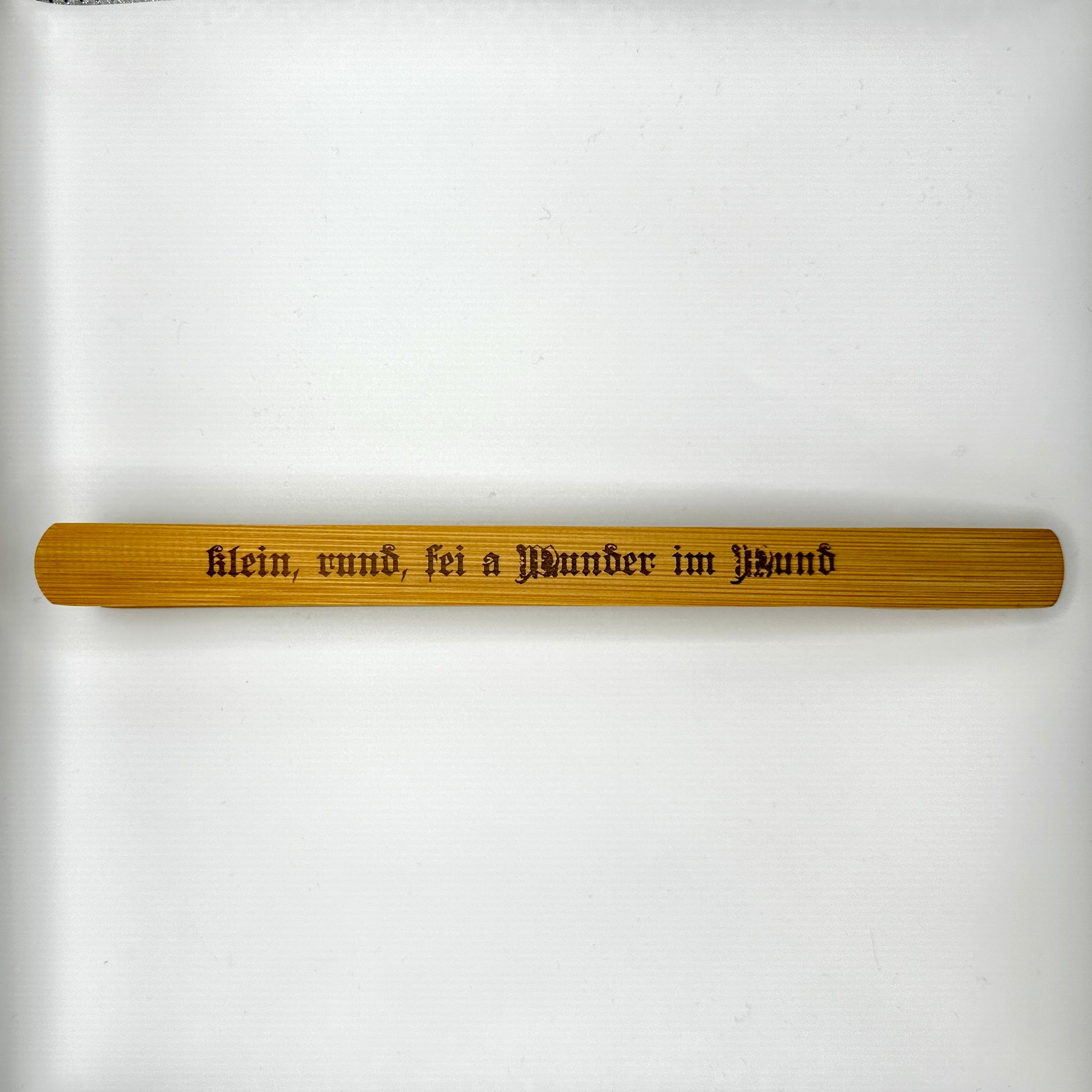Eine hochwertige Holzzange mit der Gravur „klein, rund, sei a Wunder im Mund“ in traditioneller Frakturschrift. Die Zange ist aus natürlichem Holz gefertigt und überzeugt durch ihre schlichte, elegante Form.