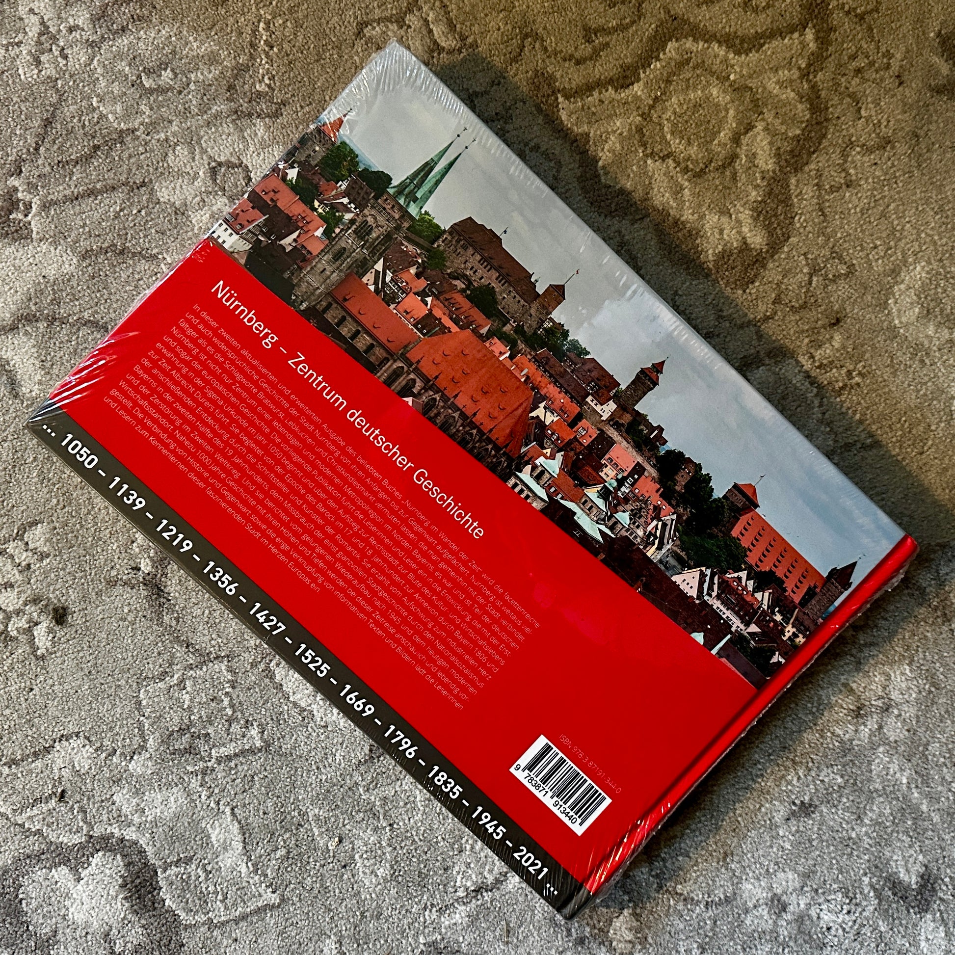 Rückseite des Buches Nürnberg im Wandel der Zeit mit einer beeindruckenden Luftaufnahme der Stadt. Der Buchrücken zeigt historische Jahreszahlen und einen Textblock zur Geschichte Nürnbergs.