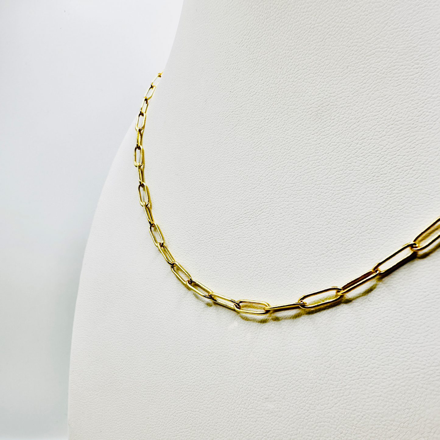 Eine vergoldete Gliederkette aus Sterling Silber liegt auf einem weißen Schmuckdisplay. Die Kette besteht aus rechteckigen, filigranen Gliedern und misst 55 cm in der Länge. Die edle 3 Micron Vergoldung verleiht ihr einen hochwertigen Glanz und macht sie zur idealen Basis für das Sammeln und Tragen von Anhängern.