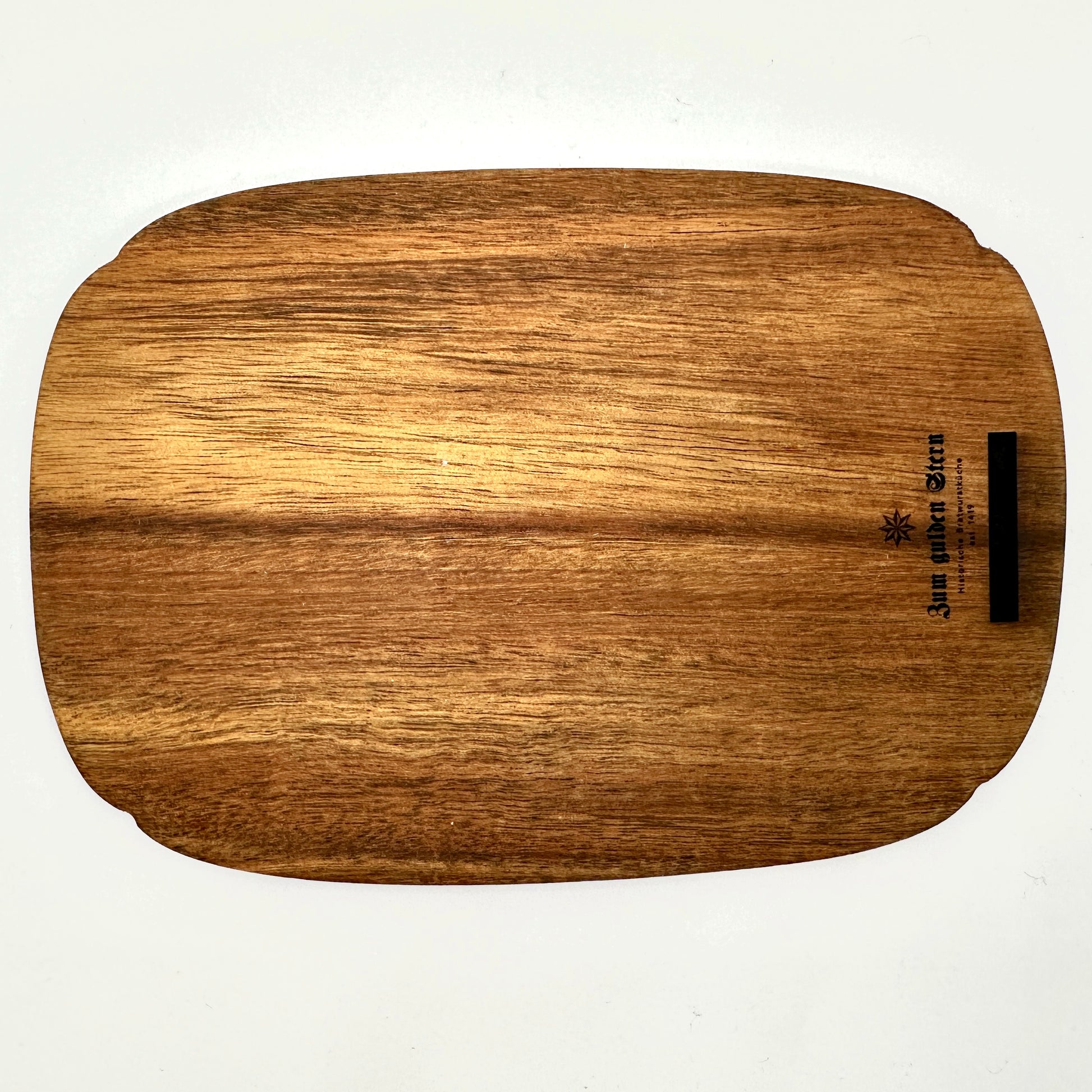 Rückseite eines hochwertigen Schneidebretts aus Holz mit natürlicher Maserung. In der oberen rechten Ecke befindet sich eine feine Gravur mit dem Schriftzug „Zum Gulden Stern“ sowie einem kleinen Sternsymbol. Das Brett hat eine sanft abgerundete Form und eine glatte Oberfläche. Ideal als stilvolles Servier- oder Schneidebrett für Liebhaber traditioneller Handwerkskunst.