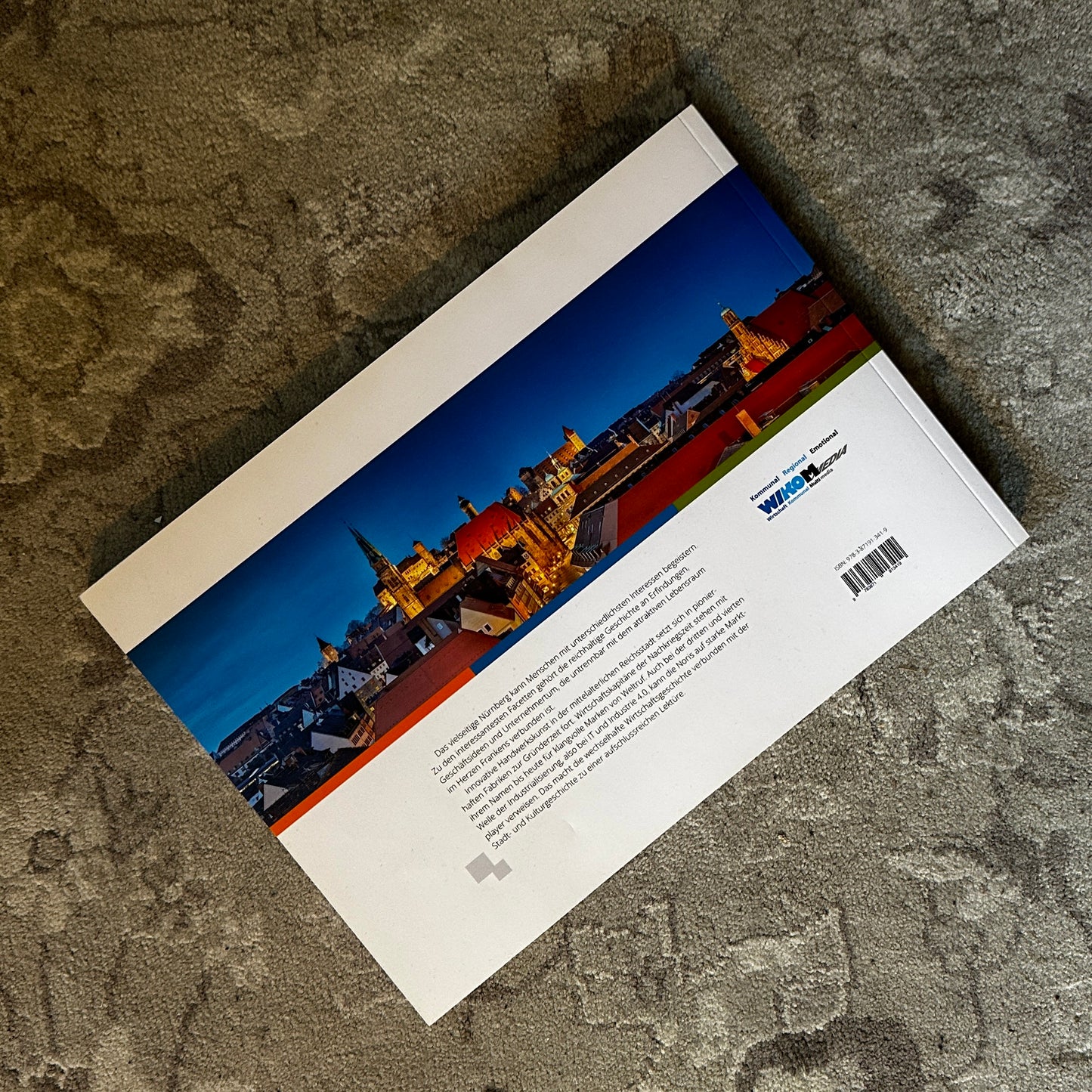 Die Rückseite eines Buches mit dem Titel „In Nürnberg“. Das Cover zeigt eine beeindruckende Panoramaaufnahme der Nürnberger Altstadt bei Nacht mit stimmungsvoller Beleuchtung. Im unteren Bereich befindet sich eine Beschreibung des Buchinhalts, begleitet vom Logo des Verlags.